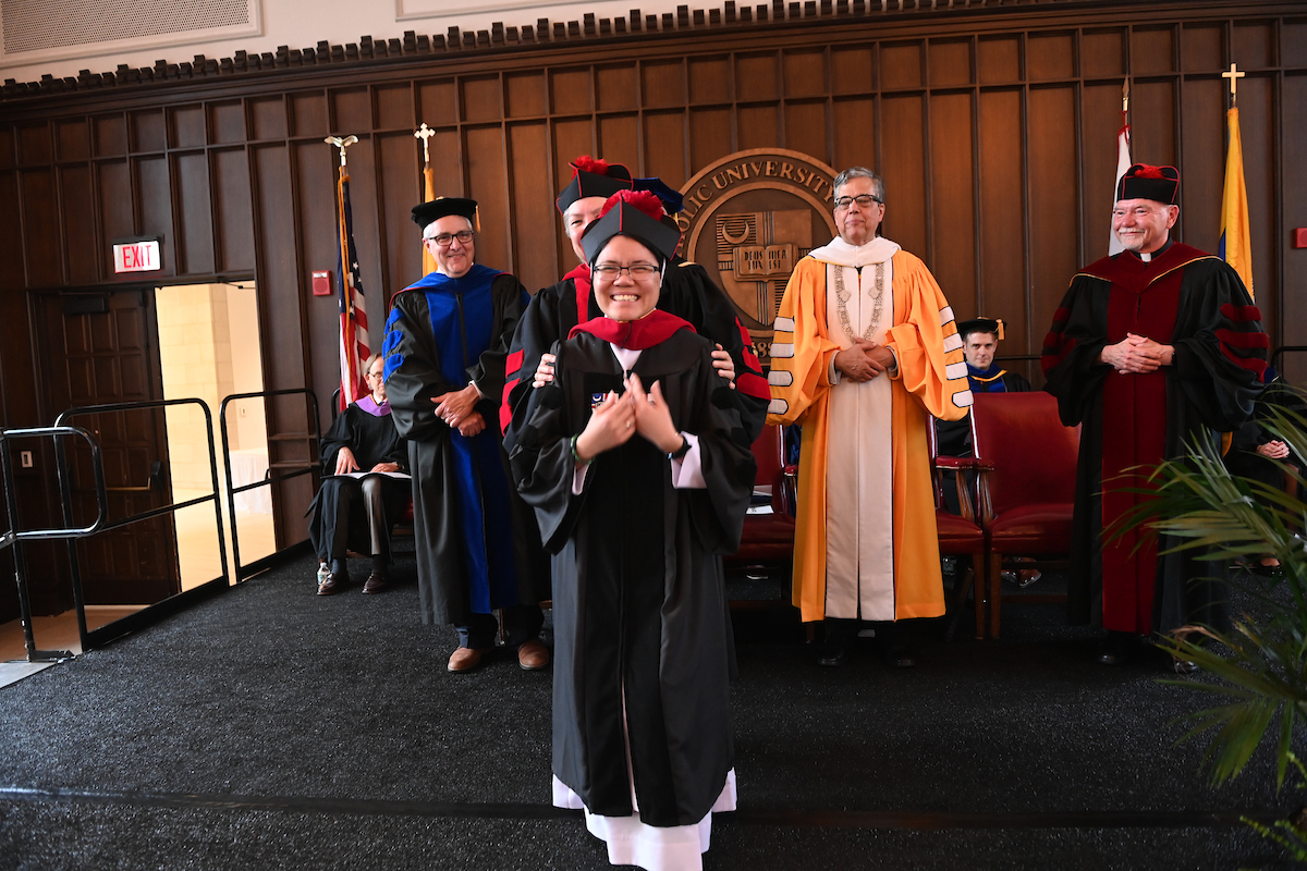 A graduate student is receiving her hood from her academic advisor during the Doctoral Hooding Ceremony.