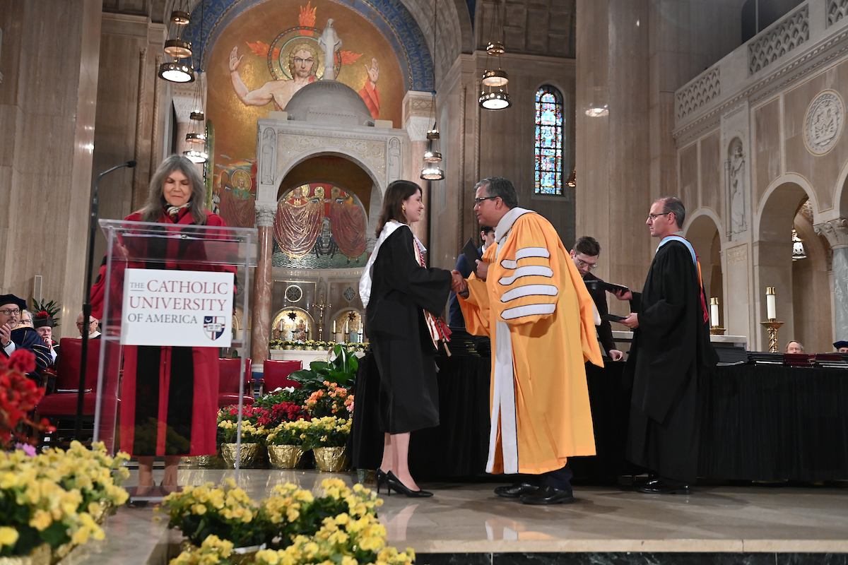 CUA President Peter Kilpatrick congratulates a student receiving an award at the Honors Convocation.