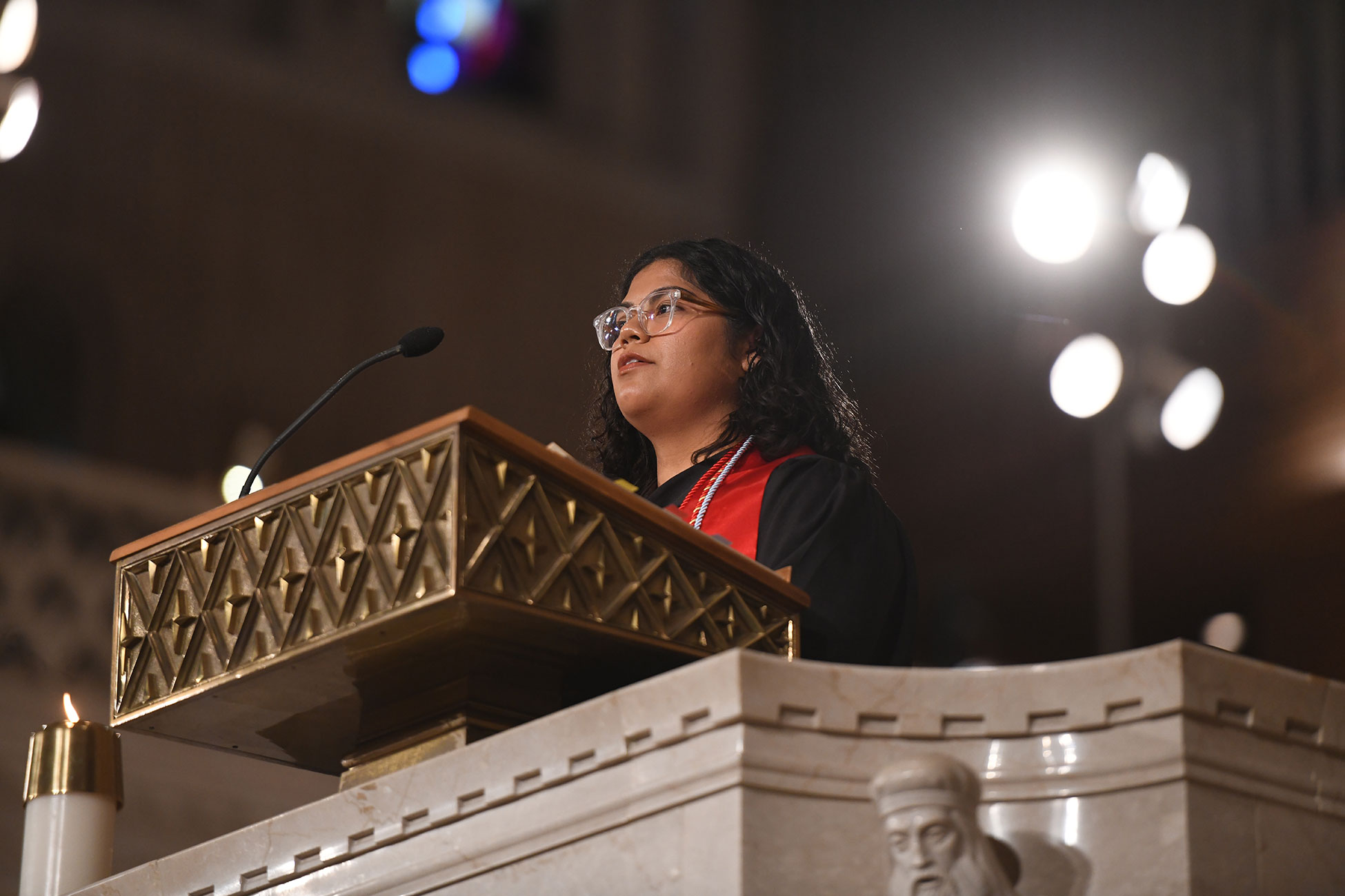 A graduate of Catholic University is leading Mass, standing at the lecturn.