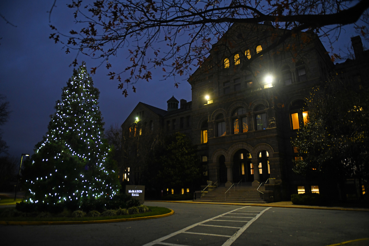 A dark winter night at Catholic University, with the large pine tree in front of McMahon covered in white Christmas lights.