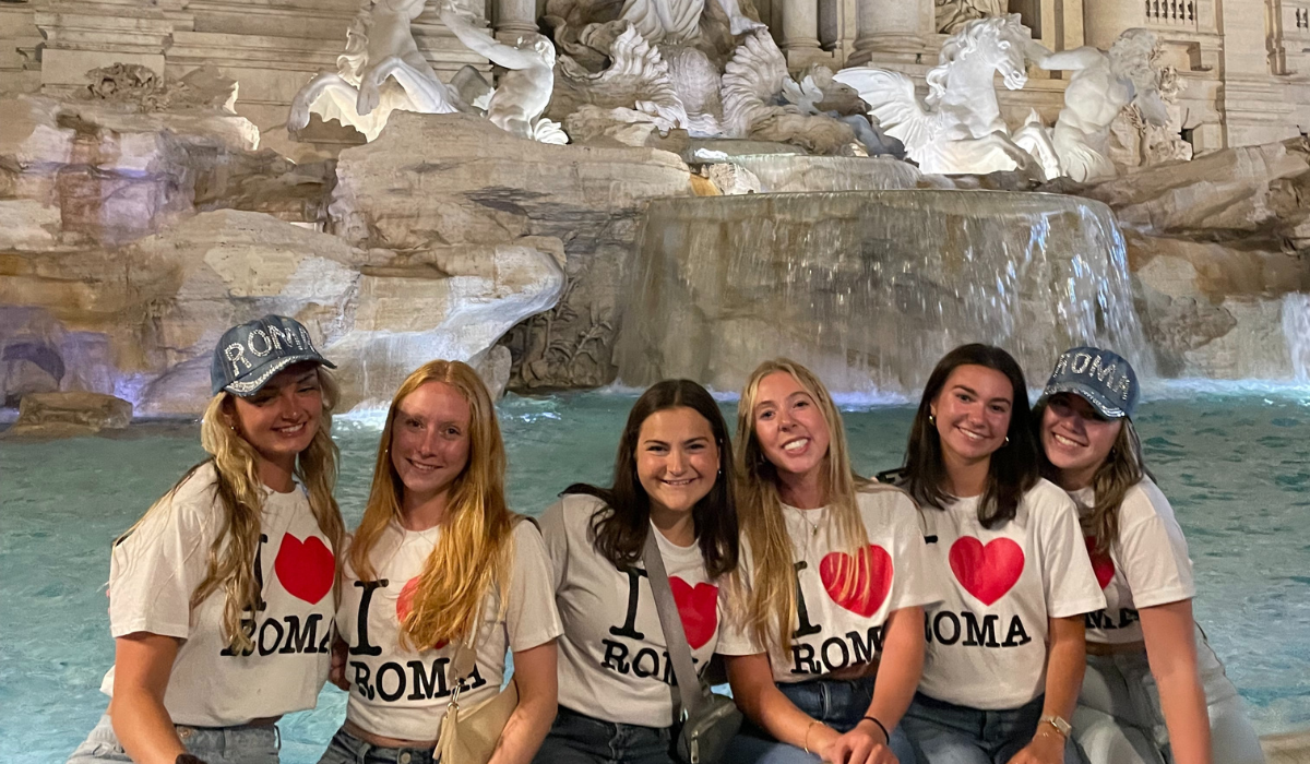 Lindsey is featured with a group of five other Catholic University students. They are all wearing "I (Heart) Roma" shirts.