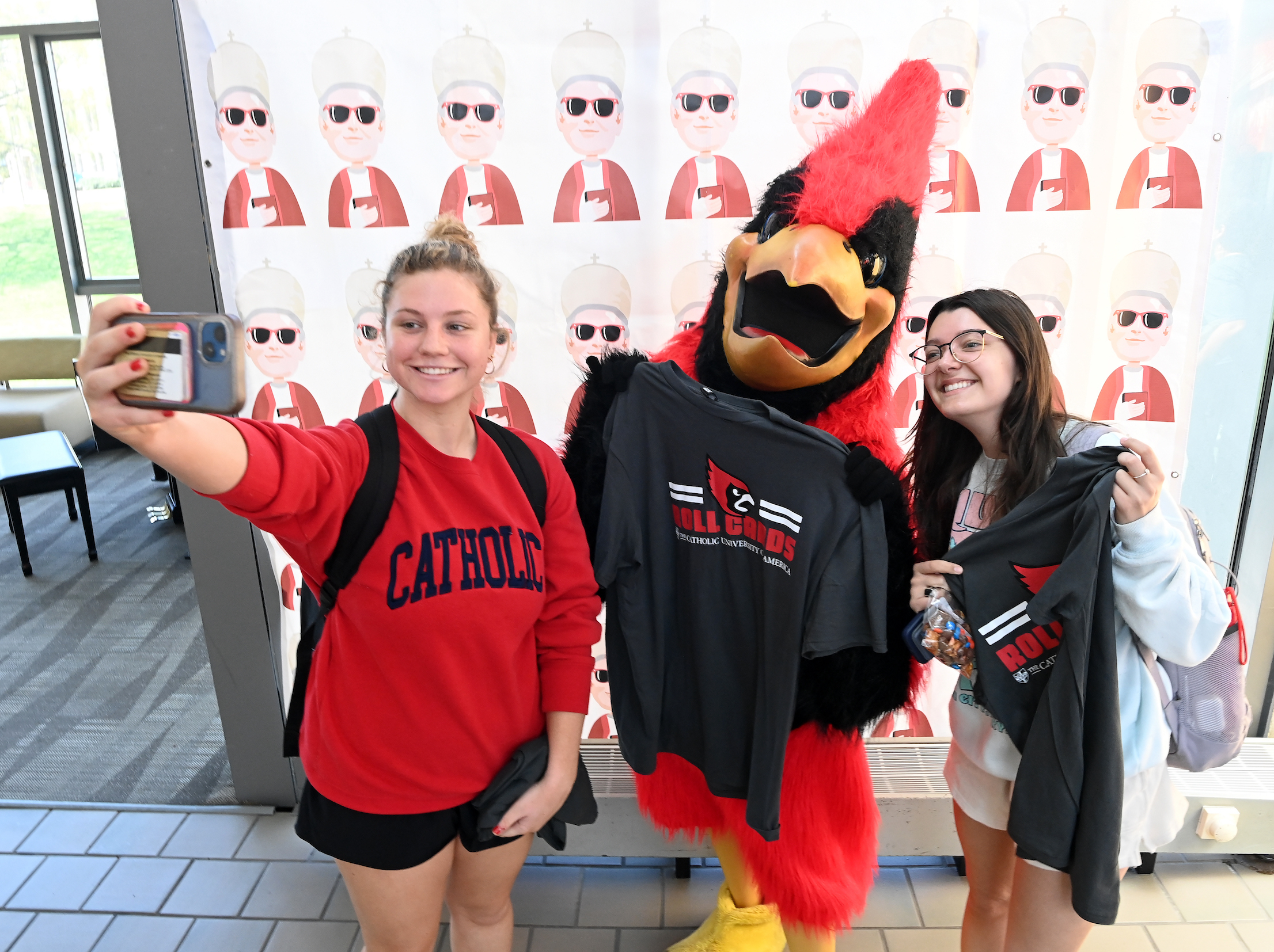 two female students taking a selfie with Red, the mascot
