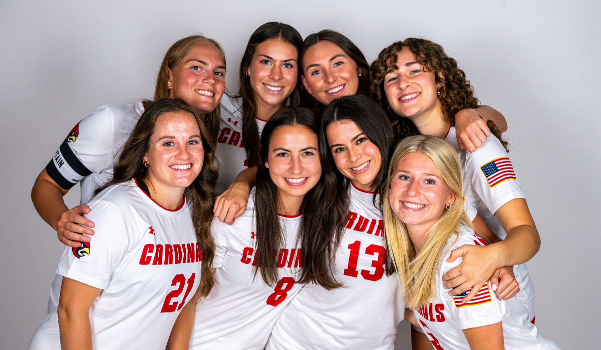 Isabella with the CUA Women's Soccer team, all in white and red uniforms.