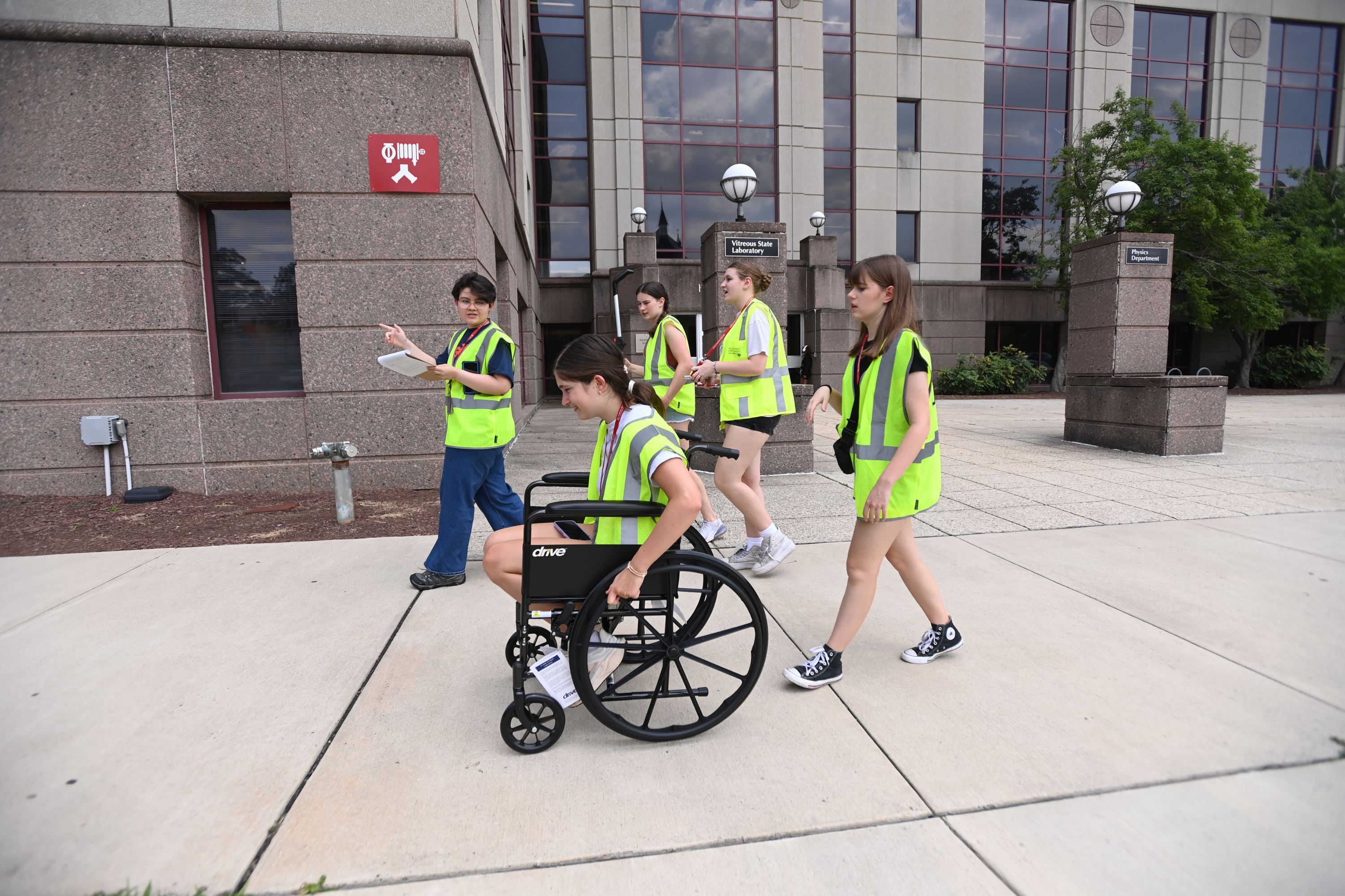 high school students use a wheelchair to test out accessibility