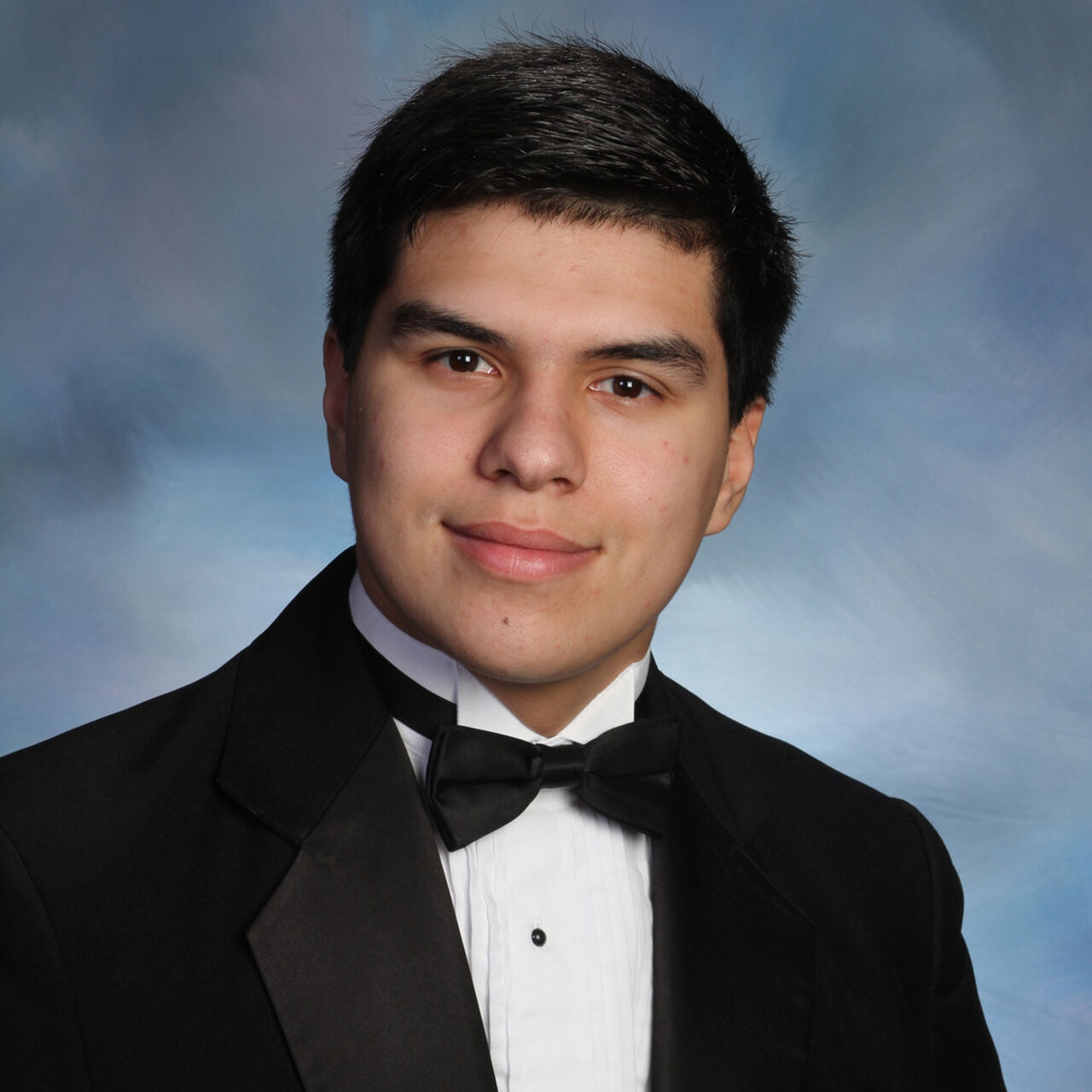 Daniel Anderl is wearing a black tuxedo against a blue background.
