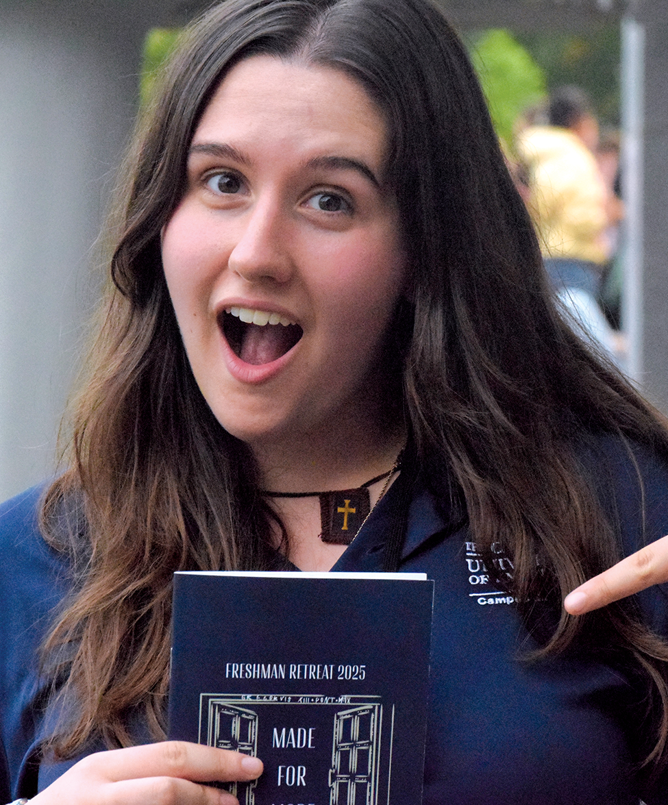 a student holds a pamphlet for Freshman Retreat