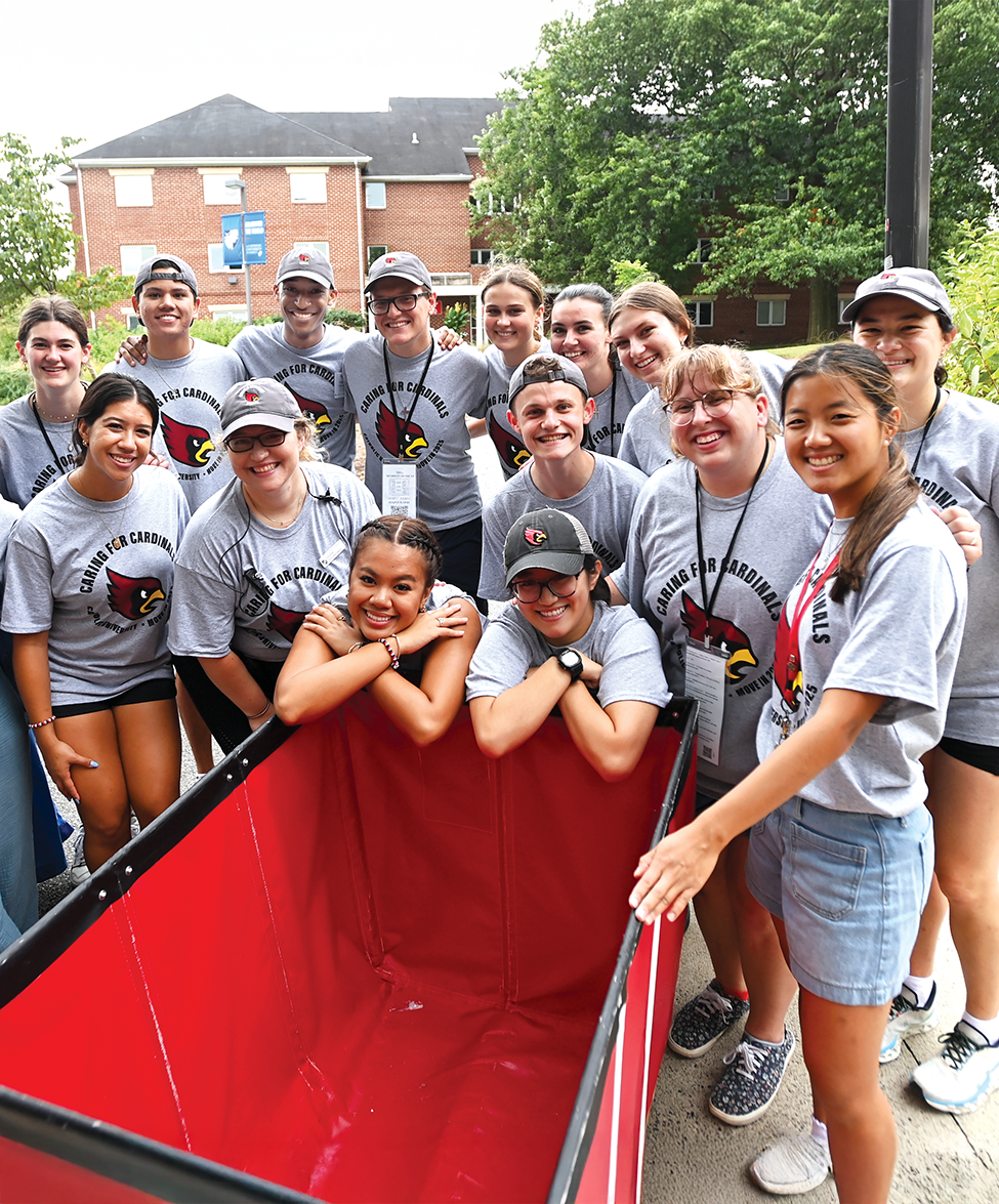 a group of student move-in volunteers gathers around a large bin used to help students move into their dorms