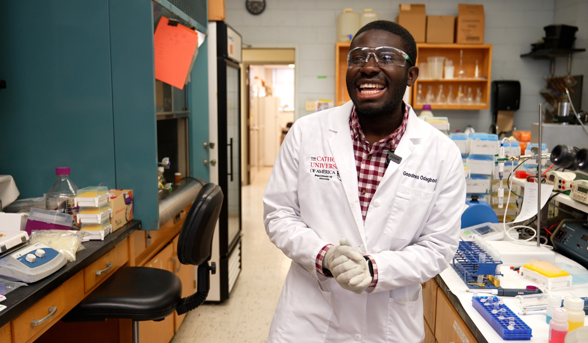 Goodness Odagbodo in the lab, wearing a white lab coat and goggles.