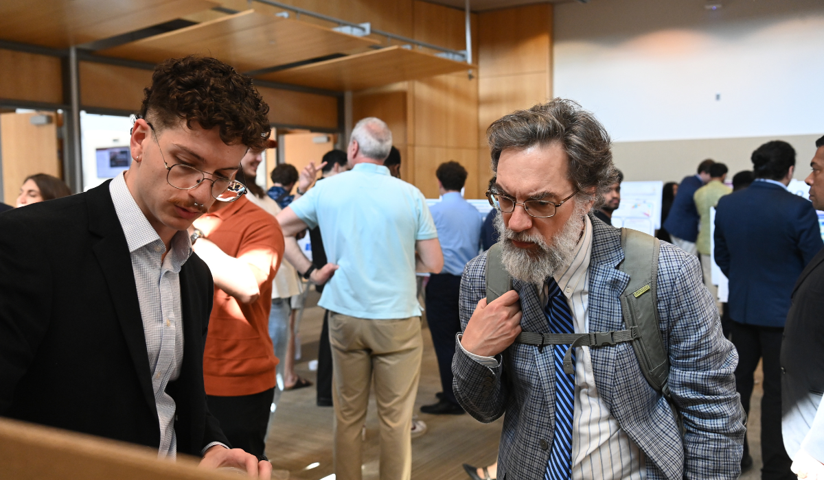 A student is showing off his presentation to a professor during URD2026.