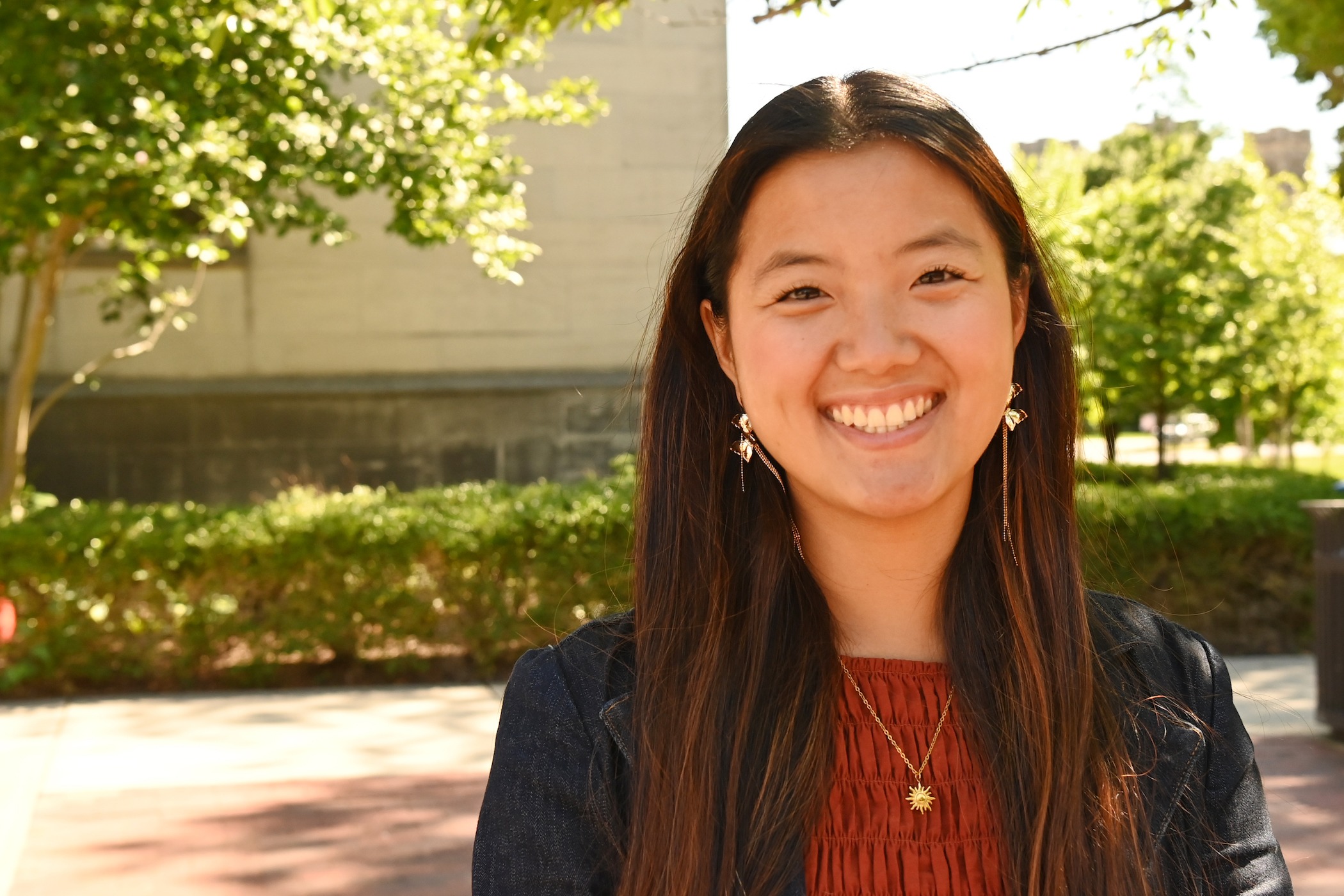 Girl smiles in sunshine on campus, wearing blue blazer