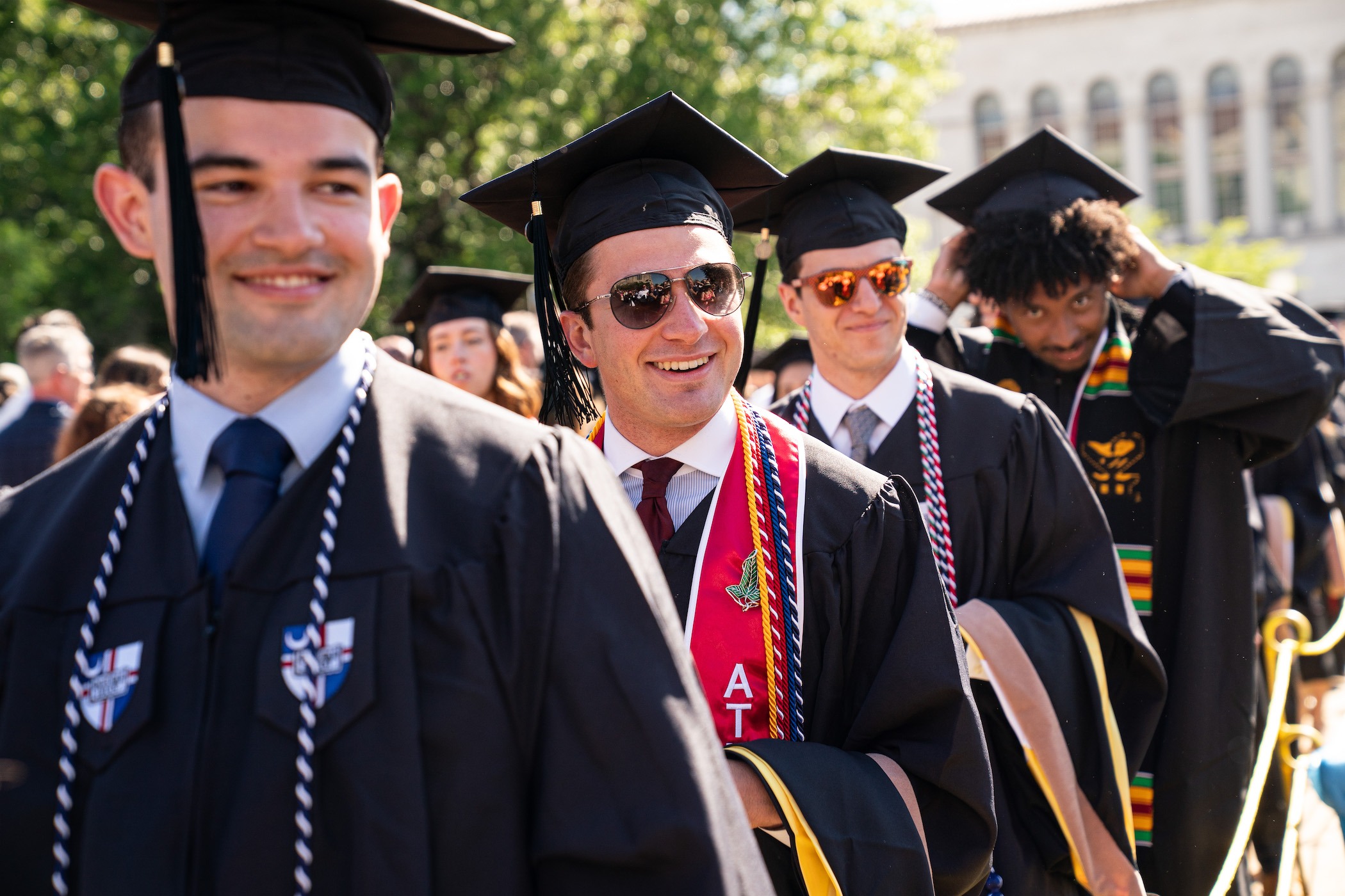 male graduates smile as they process into the commencement ceremony