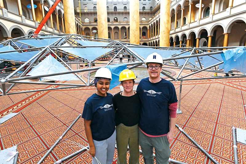 students pose for a photo at the national building museum with the wave structure in the background
