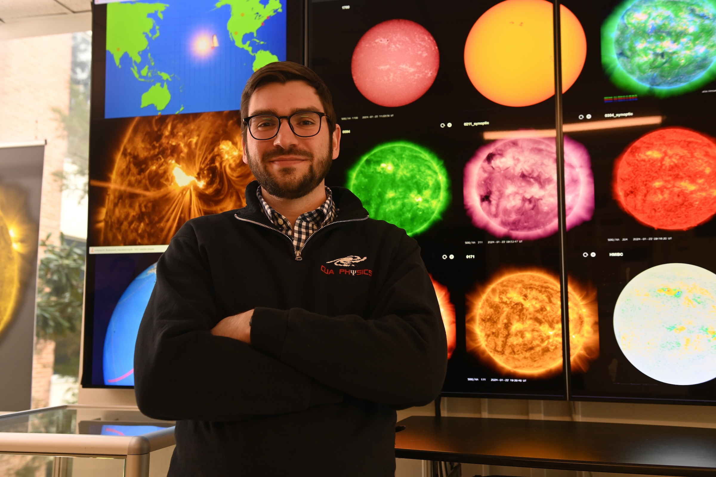 Michelangelo Romano stands before a wall of screens depicting live video of the sun in different wavelengths.
