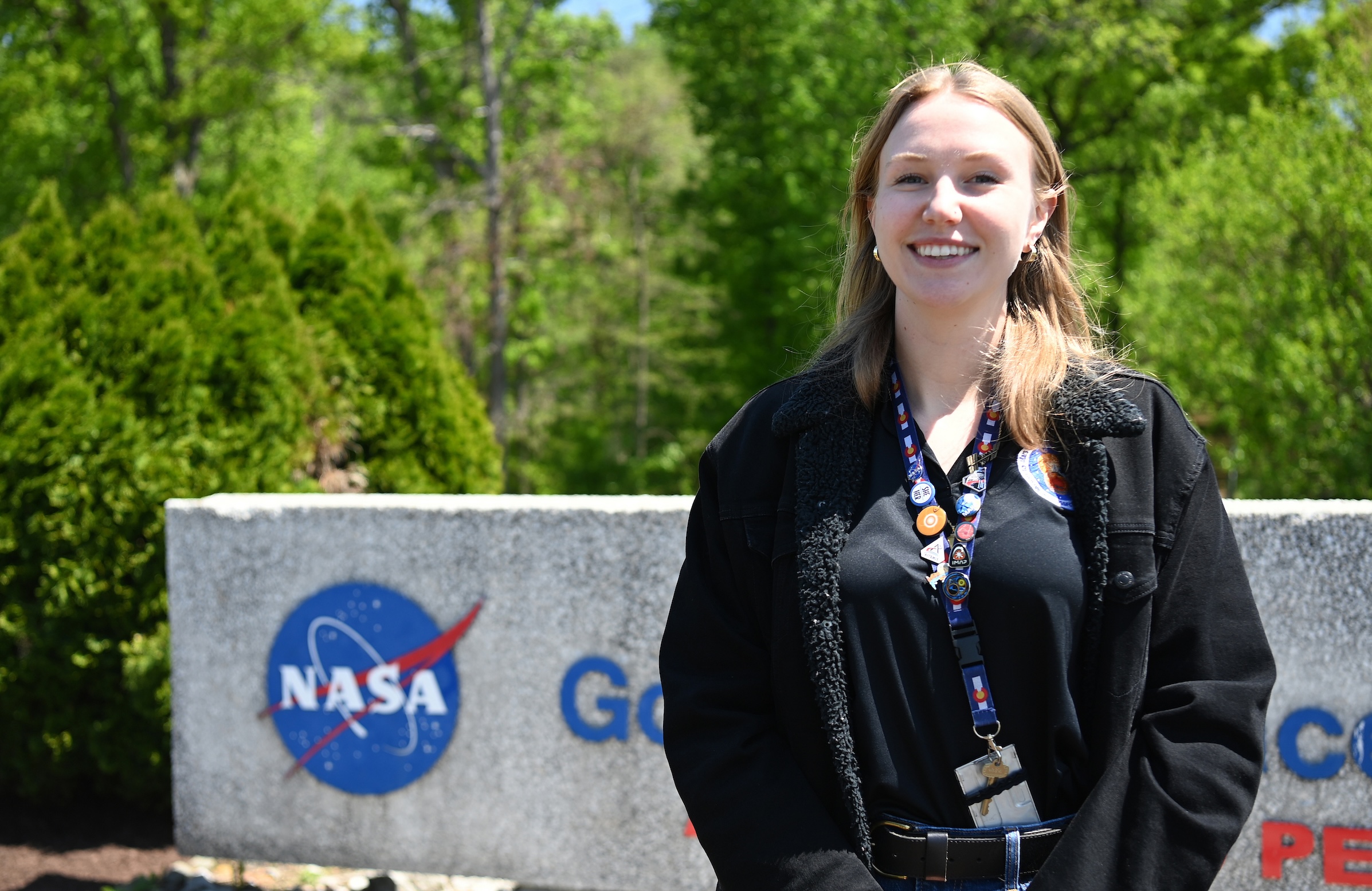 Melissa Kane stands in front of the entry sign for Goddard Space Flight Center