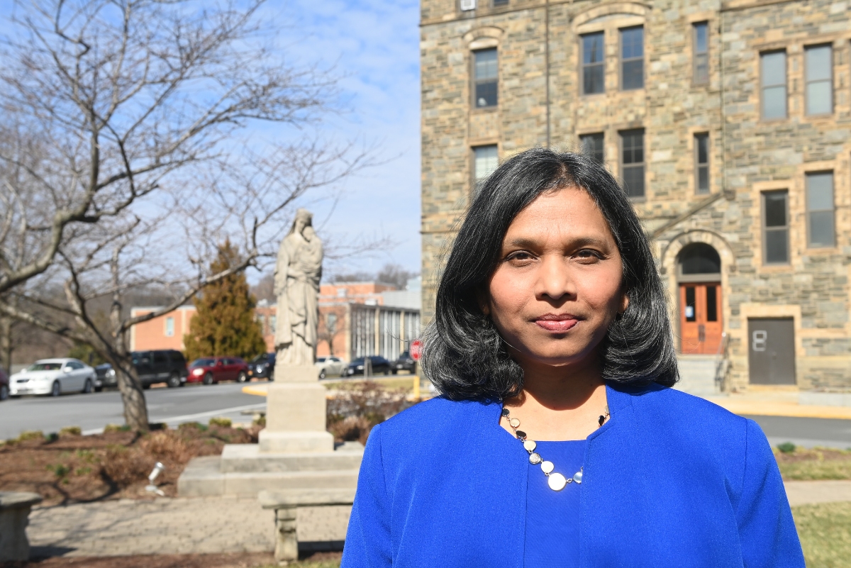 Photo of Dr. Jem Rosario Sullivan in blue dress outside Caldwell Hall