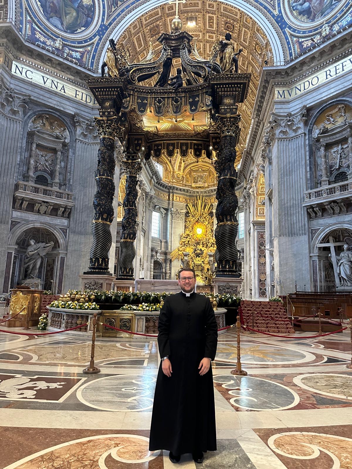 dillon johnson in his cassock inside an empty St. Peter's Basilica