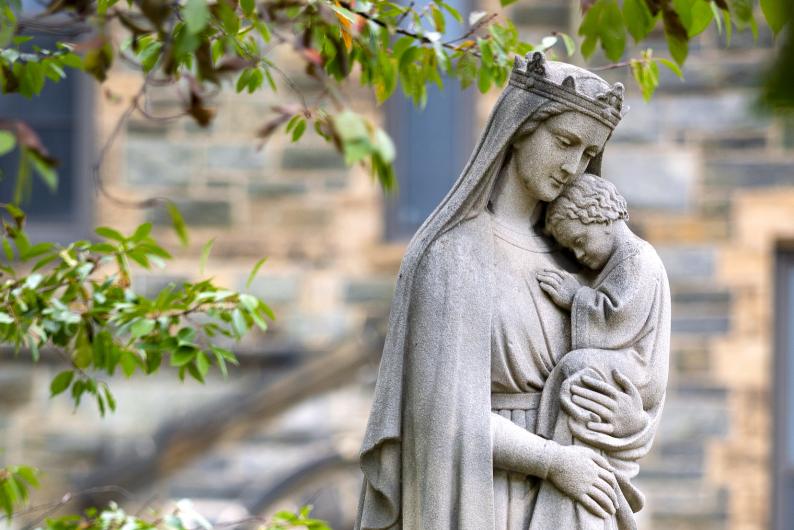 Stone statue on campus of the Virgin Mary holding Jesus 