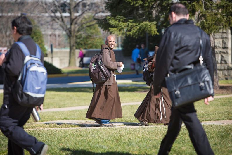 franciscan brother walks across campus in his habit