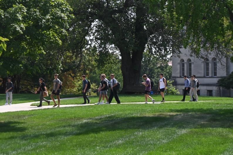 students walking across a tree-covered part of campus