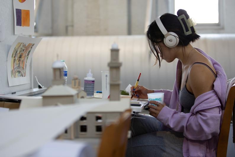 student working on a project while wearing headphones