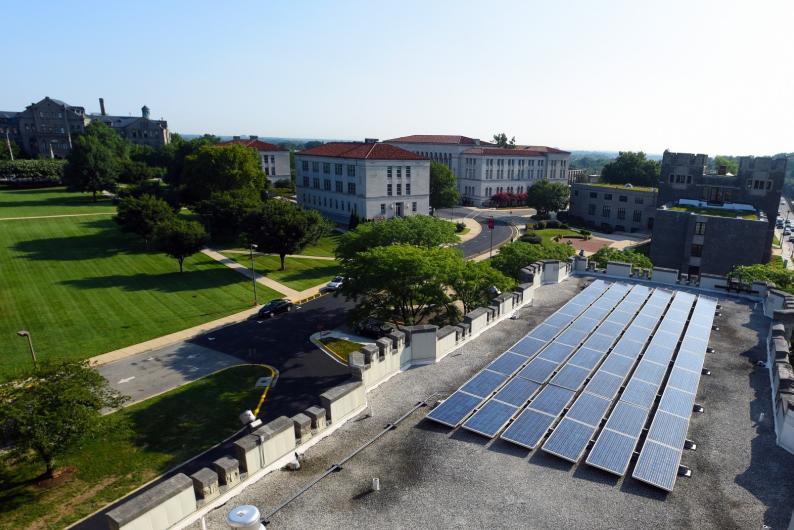 aerial view of solar panels on a roof and a green lawn on campus