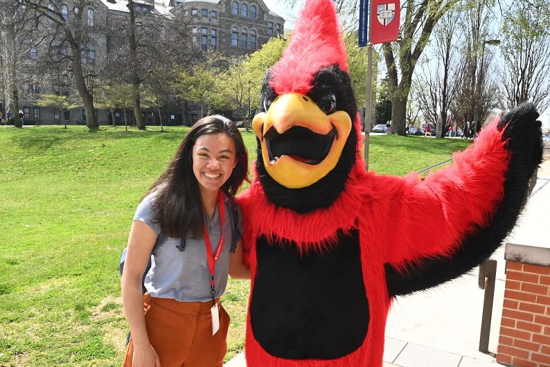 student takes a picture with Red the cardinal, the catholic university mascot