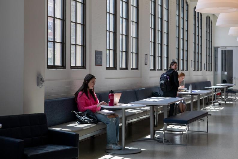 student studying by windows in the business school building