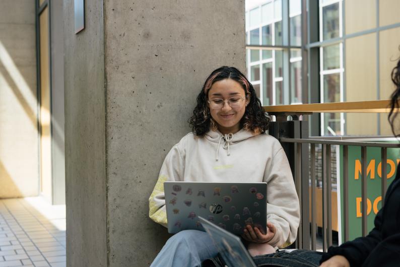 student smiling and working on her laptop
