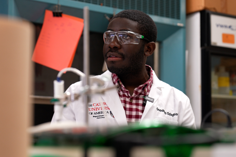 Goodness Odagbodo in the lab, wearing a white lab coat and goggles.