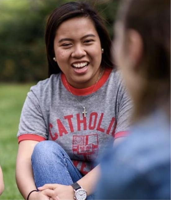 Student smiling and sitting on the lawn