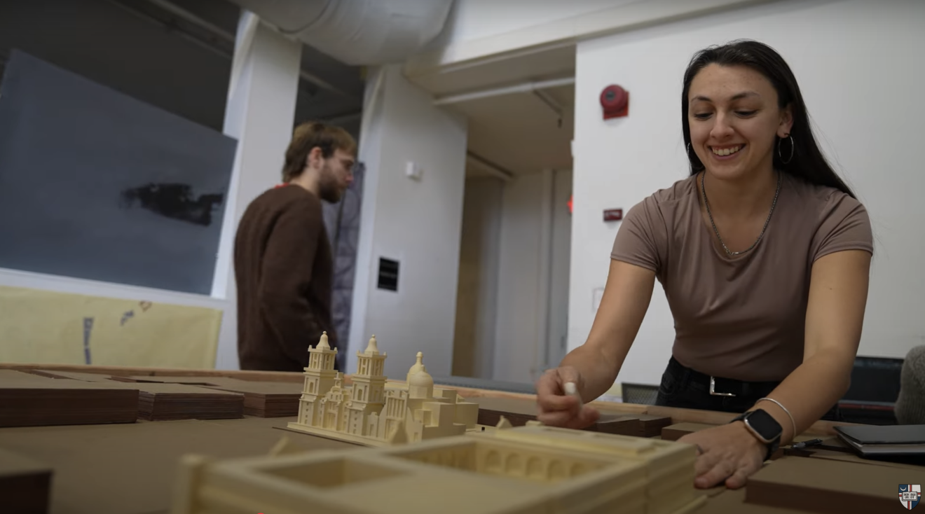 Elizabeth is looking over a wooden model.