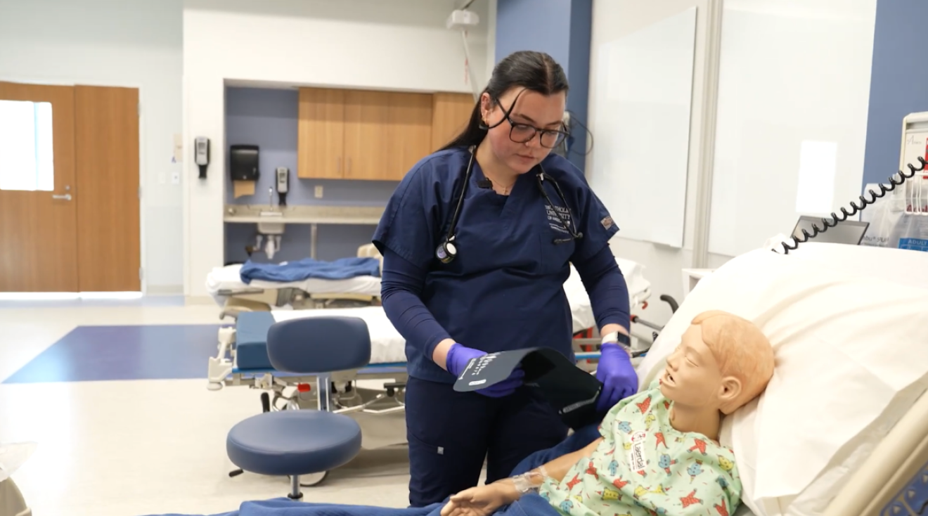 Megan Stake is attending a mannequin patient in the simulation lab.