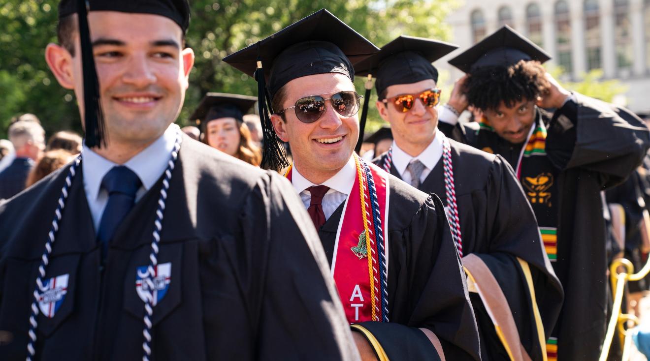male graduates smile as they process into the commencement ceremony